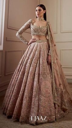 a woman in a pink and gold lehenga with her hands on her hips