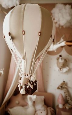 a white hot air balloon hanging from the ceiling in a room filled with stuffed animals