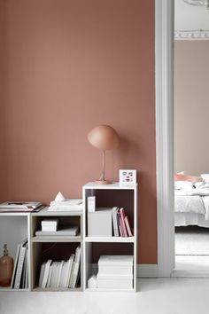 a white book shelf sitting next to a pink wall