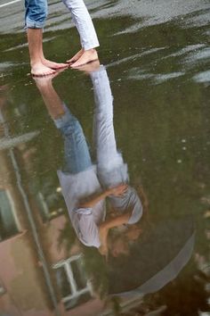 a man standing in the middle of a puddle with his hands on his head and feet above water