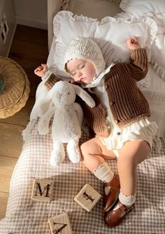 a baby laying on top of a bed next to a teddy bear and letter blocks