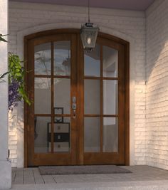 a large wooden door sitting next to a white brick building with glass panels on it