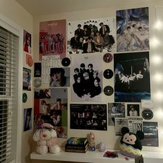 a white shelf topped with lots of pictures and stuffed animals next to a window covered in lights