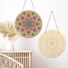 two circular wall hangings on a white wall next to a potted palm plant