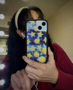 a girl is holding up her phone case with stars on it and the sky in the background