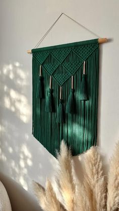 a green wall hanging with tassels on it