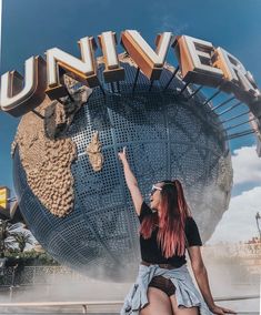 a woman sitting on the ground in front of a giant sign that reads univerl