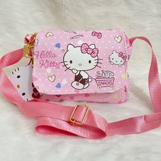 a pink hello kitty purse with a small white cat on it's shoulder strap