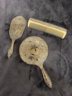 two antique hair combs and a mirror on a bed