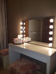 a vanity with lights on it and a stool in front of the mirror that is lit up