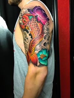 a man with a tattoo on his arm has a koi fish and flowers in it