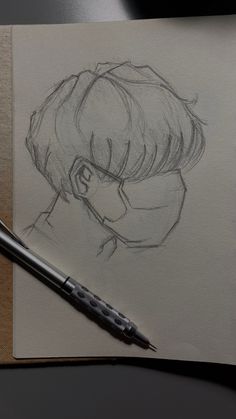 a pencil drawing of a boy with glasses on top of a piece of paper next to a pen