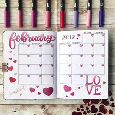 an open planner with hearts and the word february written in pink on it, surrounded by markers