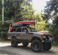 an suv with a kayak on the roof is parked in front of a wooded area