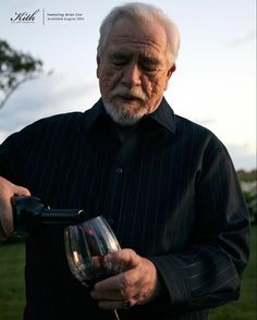 an older man holding a wine glass in his hand