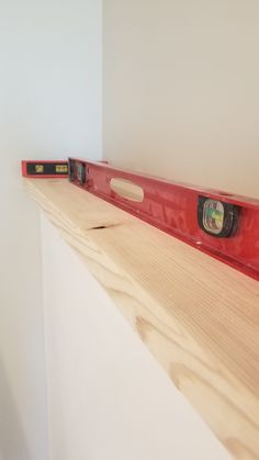 a wooden shelf with two red rulers on it