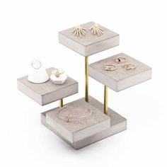 three tiered trays with rings and jewelry on them, one is white and the other is gold