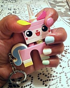 a person holding a small toy in their hand with a keychain attached to it