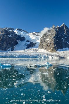 icebergs floating in the water with mountains in the backgrounnd and snow on the ground