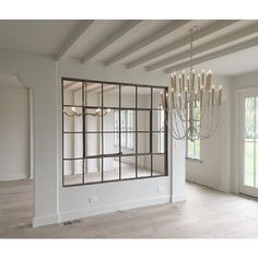 an empty living room with chandelier and windows