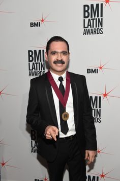 a man in a tuxedo with a medal around his neck standing on a red carpet