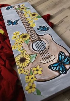 a painting of a guitar with sunflowers and butterflies painted on the back side