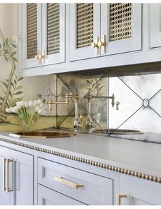 a kitchen with white cabinets and gold accents