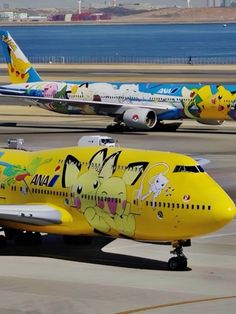 two yellow planes with pokemon painted on them are sitting on the tarmac at an airport