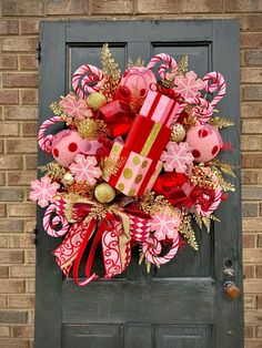 a christmas wreath with candy canes and presents on it in front of a door