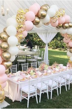 a table set up for a party with pink and gold balloons on the top of it