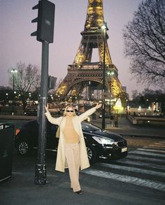 a woman standing next to a pole with the eiffel tower in the background