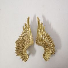 two gold angel wings on a white surface