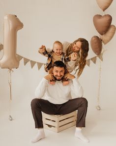 a man sitting on top of a wooden crate with two women and a baby in his arms