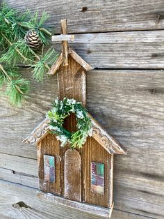 a small wooden house hanging on a wall next to a pine cone and fir tree