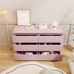 a pink dresser sitting on top of a hard wood floor next to a white rug