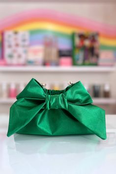 The Mimi Bow Clutch in Kelly Green is super lightweight and large enough to hold all your essentials. Featuring a satin fabric, a statement bow, a magnetic closure, and a detachable gold shoulder strap chain, this bag is perfect for a brunch, or evening out on the town. Handmade in Charleston, South Carolina by Mimi's mom, Keiko! This listing is for one 5" x 9”x 3” clutch. Chic Party Bag With Ribbon Detail, Chic Party Bag With Ribbon, Evening Bags With Bow Detail, Chic Evening Shoulder Bag With Bow, Chic Formal Bags With Satin Bow, Elegant Party Bag With Satin Bow, Elegant Party Bags With Satin Bow, Chic Bag With Bow For Gift, Chic Gift Bag With Bow Detail