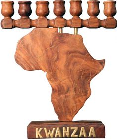 a wooden sculpture with seven candles on it's head and the word kwanzaa written in gold