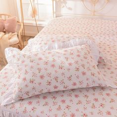 three pillows stacked on top of each other in front of a bed with pink flowers