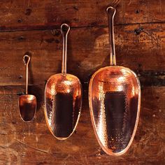 three copper colored pots and spoons hanging from hooks