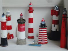 there are many small lighthouses on the shelf in front of each other, including one red and white