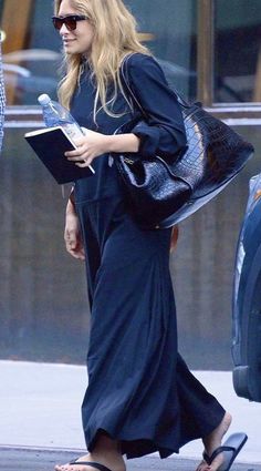 a woman walking down the street with a book in her hand