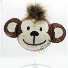 a stuffed monkey head on top of a metal stand with a white base and brown ears