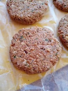 four cookies sitting on top of a piece of wax paper next to some type of food