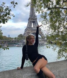 a woman posing in front of the eiffel tower with her legs spread out