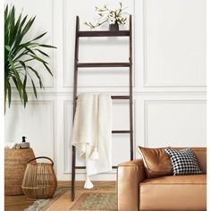 a living room with a leather couch and wooden ladder next to a potted plant