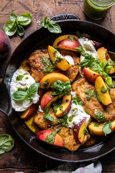 a skillet filled with chicken, peaches and sour cream sauce on top of a wooden table