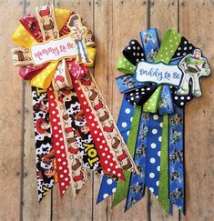 two colorful ribbons are sitting on a wooden surface, one has a name tag and the other has a bow