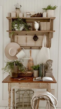 an old wooden table topped with pots and pans filled with plants next to a wall mounted shelf