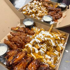 two boxes filled with chicken wings covered in sauces and ranch dressing on top of each other