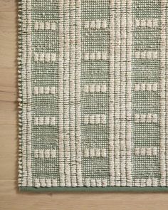 a green and white rug on top of a wooden floor